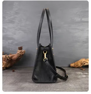 Detailed side view of black leather shoulder bag showing hardware and strap construction.