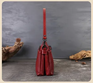 Side detail view of red multi-layer leather shoulder bag with structured compartments.