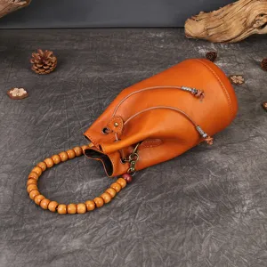 Orange leather bucket bag with wooden bead handle, retro vintage drawstring crossbody bag.