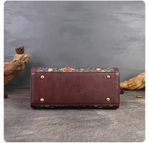 Detailed bottom view of vintage floral embroidered leather handbag with metal protective feet.
