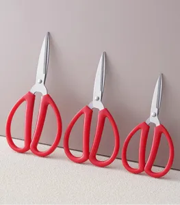 Close-up detail of three red-handled multi-size household scissors with sharp steel blades.