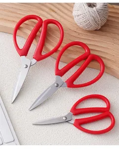 Detail view of household stainless steel scissors with red handles, sharp blades for cutting.
