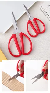 Detail view of household office scissors with red handles and sharp stainless steel blades.
