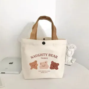 Compact canvas tote bag featuring cute cartoon bears and brown handles for daily use.