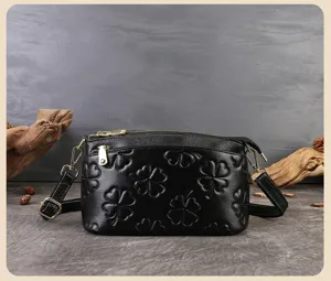 Dettaglio borsa a tracolla in pelle nera con motivo trifoglio goffrato e metallo.