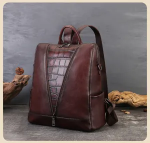 Close-up of a dark brown leather backpack featuring a crocodile embossed panel and zipper.