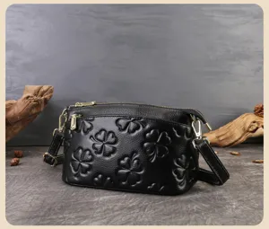 Primo piano della borsa in pelle nera con motivo a trifoglio goffrato e dettagli metallici.