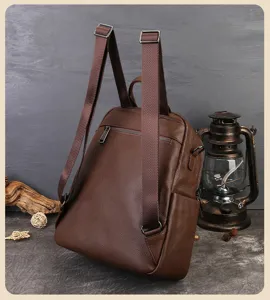 Vue détaillée du sac à dos en cuir véritable marron foncé avec bretelles et zips métalliques.