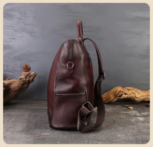 Detailed side view of brown leather backpack showing fine texture and durable stitching details.