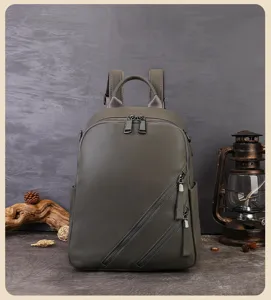 Vue détaillée du sac à dos en cuir véritable vert foncé avec poches zippées diagonales et poignée.
