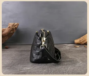 Borsa a mano nera vista laterale con motivo a griglia testurizzato, cerniera e minuteria metallica.