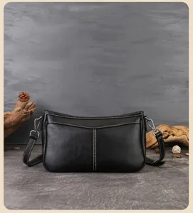 Detailed view of black genuine leather underarm bag with neat stitching and metal hardware.