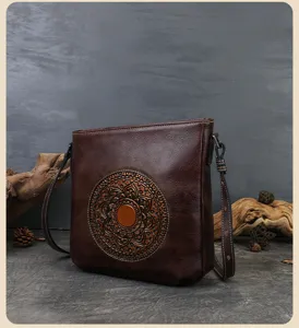 Detailed view of vintage embossed leather shoulder bag with circular totem design and strap.
