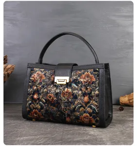 Vintage embroidered top handle bag with floral pattern, black leather trim and metal clasp closure.