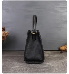 Detailed side view of a black vintage leather handbag showing structured shape and handle.