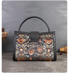 Vintage floral brocade top-handle handbag with black leather trim and structured design.