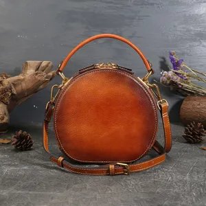 Vintage round leather handbag for women, top handle shoulder crossbody bag with retro design.