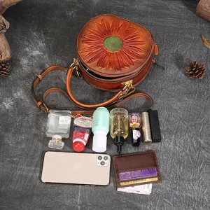 Vintage leather round crossbody bag for women, stylish embossed floral shoulder handbag.