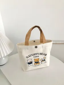 Cute cartoon bear printed canvas tote bag detail view with contrast brown handles and snap button.