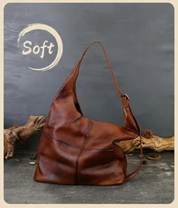 Detail view of vintage genuine leather slouchy tote bag, soft cowhide texture and wide strap.