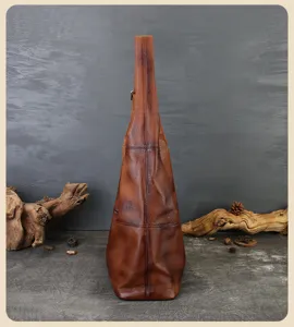 Detailed side view of vintage genuine leather hobo shoulder bag with wide strap texture.