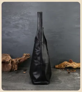 Side view of black leather tote bag with wide strap, showcasing spacious design and neat silhouette.