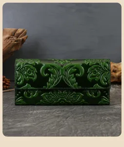 Dark green embossed genuine leather long wallet detail shot, vintage carved floral pattern.