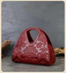 Detailed view of wine red embossed leather handbag featuring vintage floral patterns.