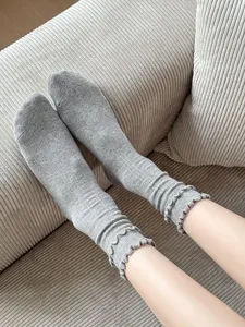 Close-up detail of cozy grey ribbed cotton socks featuring cute ruffled hems for women.