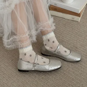 Dettaglio ravvicinato di calzini bianchi trasparenti a pois abbinati a scarpe basse argento.