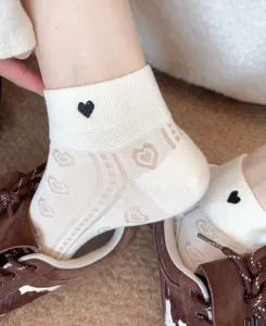 Detail view of white women ankle socks with black heart embroidery and breathable mesh heart pattern.