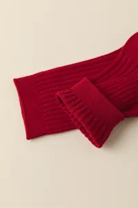 Red cotton socks knit detail closeup, ribbed cuff design, soft texture for festival wear.