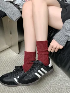Detailed close-up of thick wool slouch socks in deep red, cozy winter thermal knitwear.