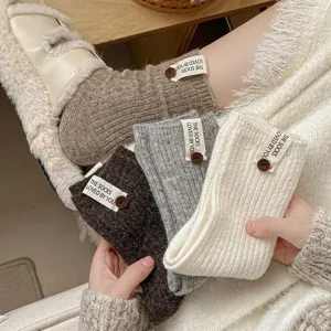 Detailed view of thick wool blend slouch socks with decorative buttons and labels.
