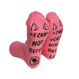 Pink fuzzy coral fleece socks detail view displaying funny cat anti-slip text soles.