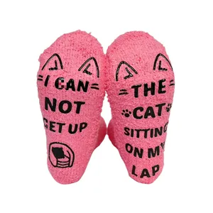 Detailed shot of pink fuzzy socks with funny quotes anti-slip grips and cat patterns.