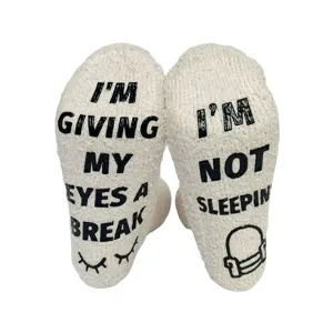 Detailed view of cozy coral fleece sleeping socks with non-slip grip lettering soles.