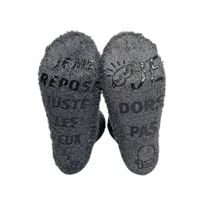Detail view of dark gray fuzzy winter sleep socks with funny French anti-slip grip text soles.