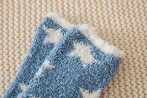 Close-up view of cozy blue coral fleece fuzzy socks with white star pattern detail.