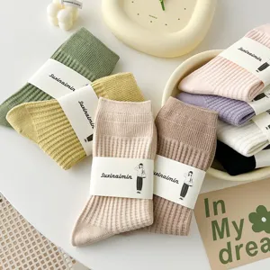 Detaillierte Nahaufnahme von Damen Waffelstrick Mittelsocken mit Papierbanderole in Pastellfarben.