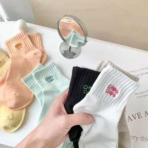 Close-up detail of women solid color ribbed cotton socks with cute embroidery text cuff.