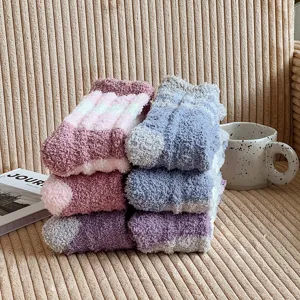 Close-up detail of cozy thick coral fleece striped winter home socks on a warm texture sofa.