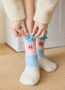 Close-up detail of cute cartoon pig coral fleece warm winter cozy mid-calf socks on feet