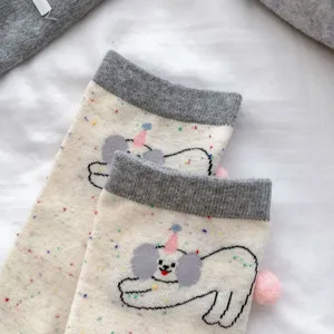 Close-up detail of cute cartoon puppy mid-tube socks with colorful speckles and pom-pom.