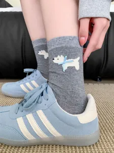Cute grey mid-tube socks featuring a sweet white puppy and blue bow detail, close-up shot.