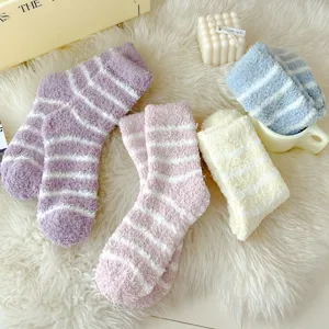 Close-up of cozy fuzzy striped plush socks in various pastel colors on a soft white blanket.