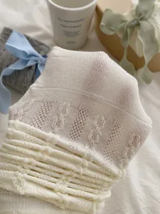 Vue détaillée de chaussettes slouch blanches à volants, texture en tricot doux.