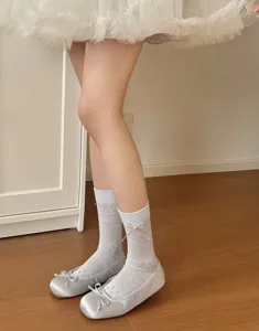 Women sweet mid-tube socks with delicate bow and mesh floral design paired with silver Mary Jane flat shoes.