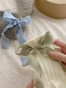 Vue détaillée de chaussettes slouch en tricot doux avec un délicat design de nœud ruban.