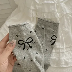 Grey ribbed mid-calf socks featuring cute black bows and heart jacquard patterns for women.